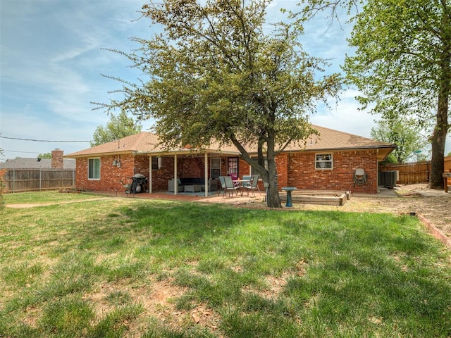 rear view of property featuring a yard, brick siding, a fenced backyard, and a patio area