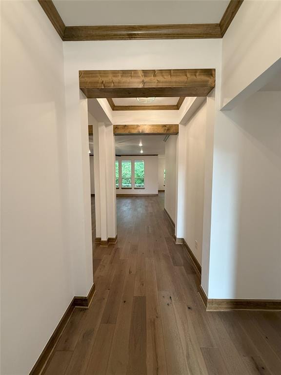 hall featuring dark wood-style floors, baseboards, and crown molding