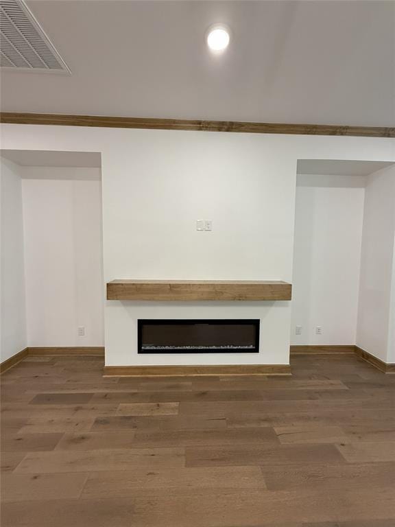 unfurnished living room with visible vents, baseboards, wood finished floors, and a fireplace
