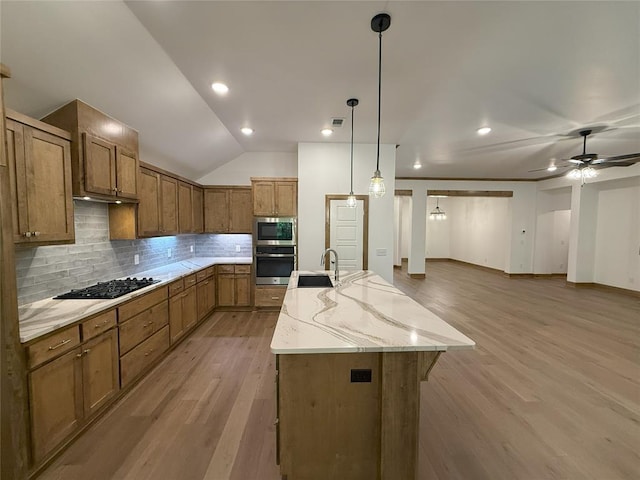 kitchen featuring light wood finished floors, brown cabinetry, open floor plan, and stainless steel appliances