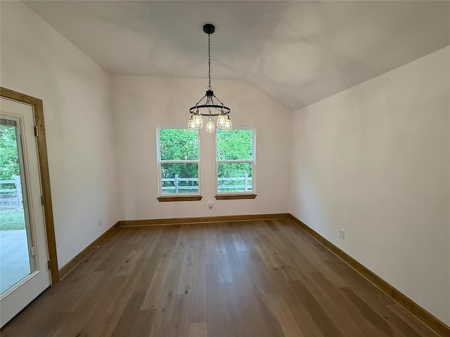 unfurnished dining area featuring dark wood-style flooring, vaulted ceiling, a chandelier, and plenty of natural light