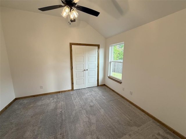 unfurnished bedroom featuring lofted ceiling, baseboards, and carpet floors