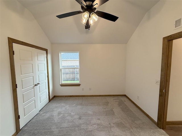 unfurnished bedroom featuring carpet, visible vents, lofted ceiling, and baseboards