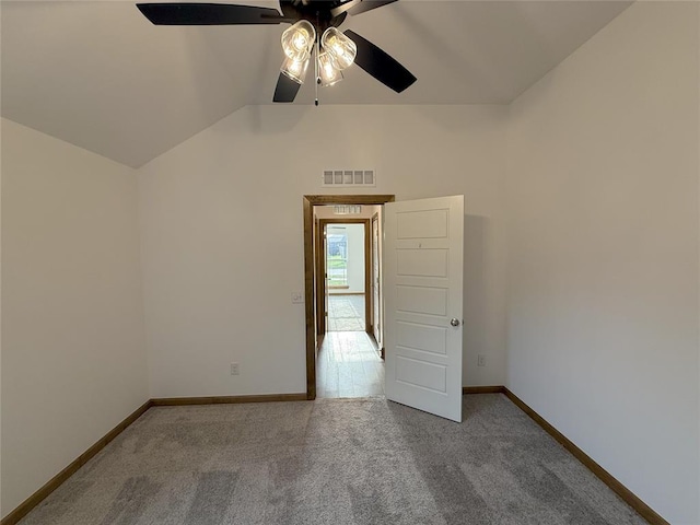 empty room featuring visible vents, ceiling fan, vaulted ceiling, and carpet floors