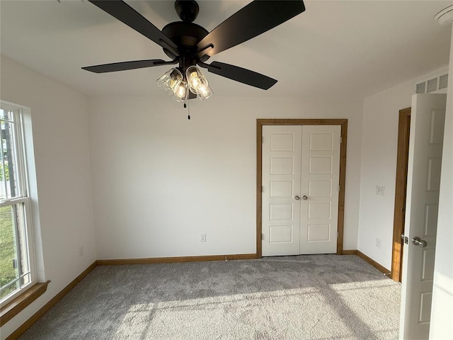unfurnished bedroom featuring multiple windows, carpet, and baseboards
