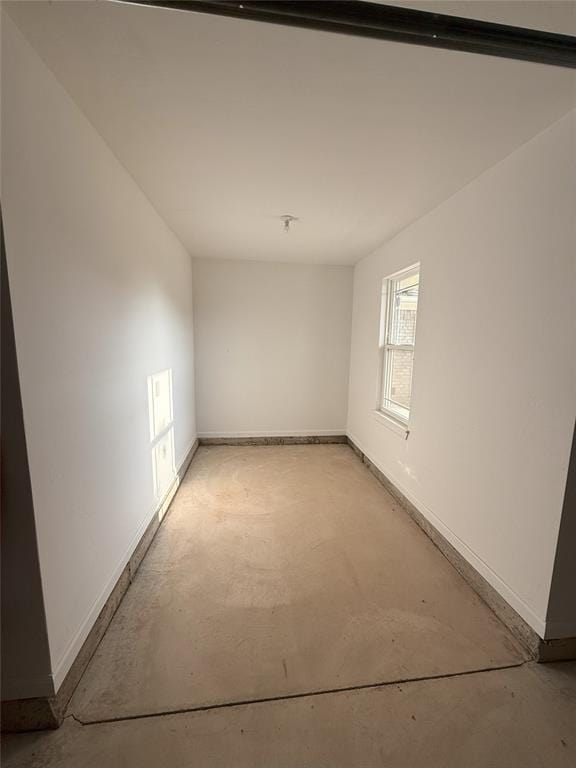 spare room featuring concrete floors and baseboards