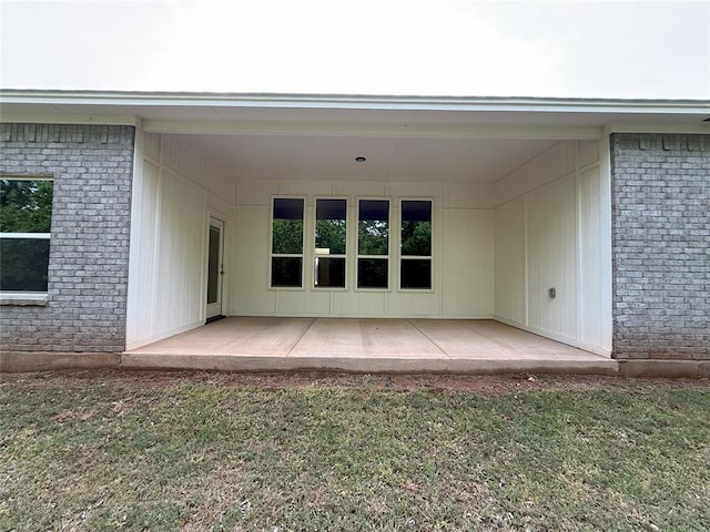 rear view of house with a patio, brick siding, and a lawn