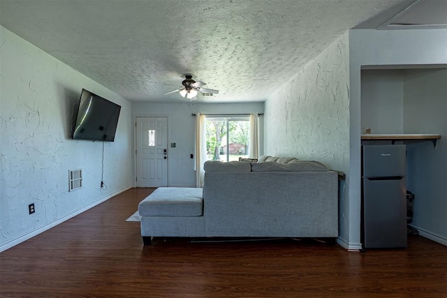 living room with a textured wall, a ceiling fan, wood finished floors, and a textured ceiling