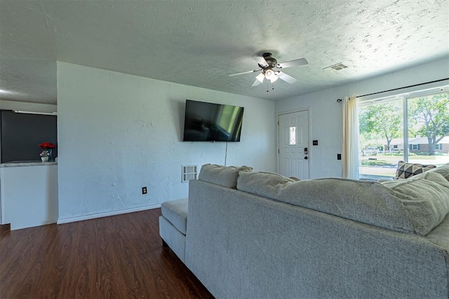 living area with a textured ceiling, wood finished floors, visible vents, and baseboards