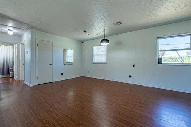 empty room with a textured ceiling and dark wood finished floors