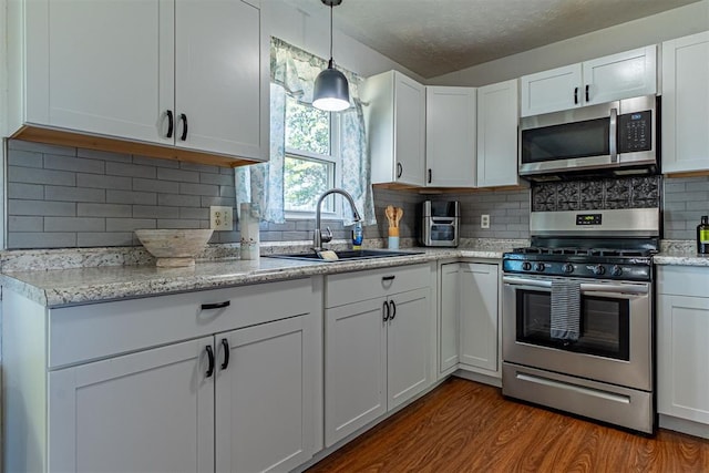 kitchen featuring a sink, tasteful backsplash, dark wood finished floors, white cabinetry, and appliances with stainless steel finishes