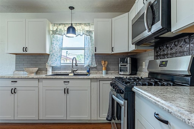 kitchen with white cabinets, stainless steel appliances, a sink, and tasteful backsplash