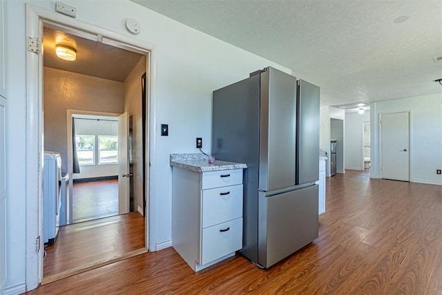 hall with washer / dryer, baseboards, a textured ceiling, and dark wood-style floors