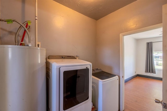 laundry area with wood finished floors, gas water heater, washer and dryer, and laundry area