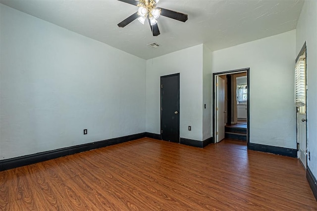 empty room featuring wood finished floors, visible vents, baseboards, and ceiling fan