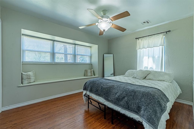 bedroom featuring baseboards, wood finished floors, multiple windows, and visible vents