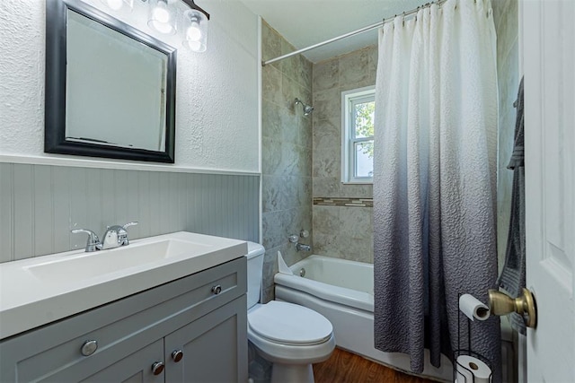bathroom featuring a wainscoted wall, toilet, shower / tub combo, wood finished floors, and vanity