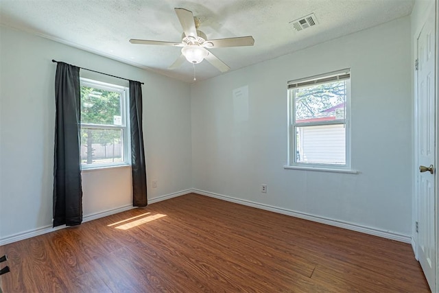 unfurnished room featuring a textured ceiling, visible vents, baseboards, a ceiling fan, and wood finished floors