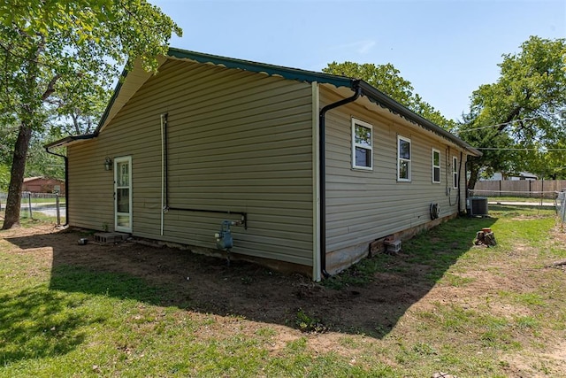 view of side of property featuring fence, a yard, and central AC unit