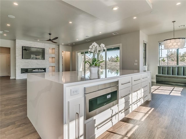 6105 NW 147th Ter, Oklahoma City, OK 73142 - kitchen featuring open floor plan, a ceiling fan, dark wood-style floors, and stainless steel microwave