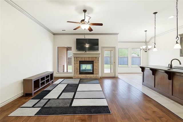 2828 Ryder Dr, Yukon, OK 73099 - unfurnished living room featuring wood-type flooring, crown molding, baseboards, and ceiling fan with notable chandelier