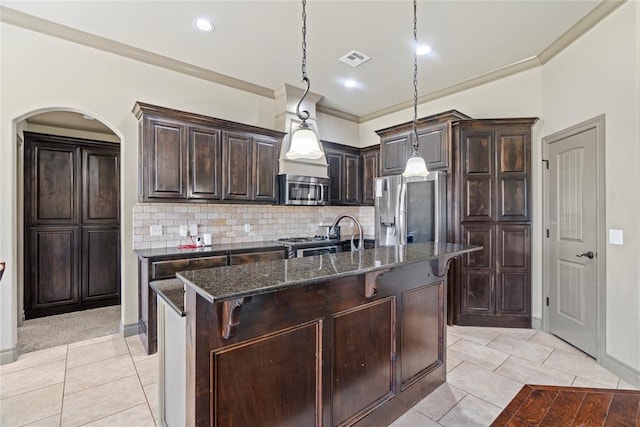 2828 Ryder Dr, Yukon, OK 73099 - kitchen with ornamental molding, dark brown cabinets, dark stone countertops, appliances with stainless steel finishes, and light tile patterned floors