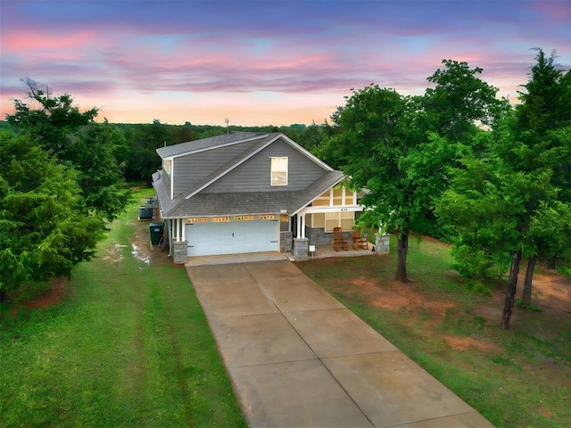 view of front of home with a lawn, roof with shingles, covered porch, and concrete driveway