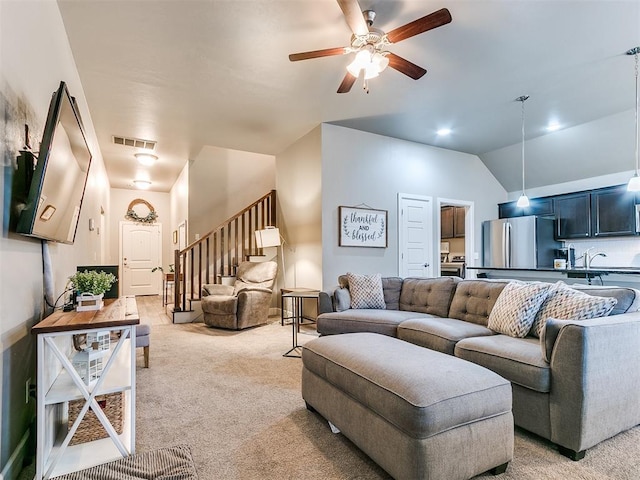 living room featuring ceiling fan, visible vents, light carpet, and stairway
