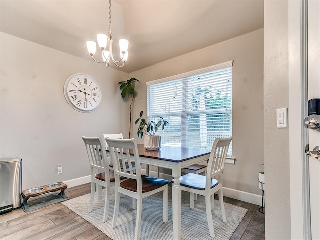 dining space with baseboards, wood finished floors, and a notable chandelier
