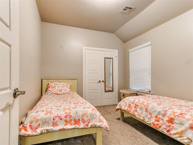 carpeted bedroom with visible vents, vaulted ceiling, and a closet