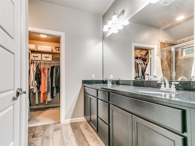 full bathroom with a sink, double vanity, lofted ceiling, a spacious closet, and a stall shower
