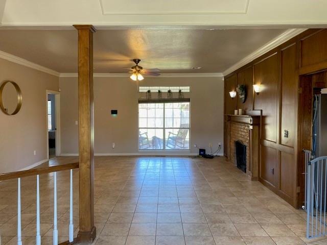 unfurnished living room featuring ceiling fan, a brick fireplace, ornate columns, and ornamental molding