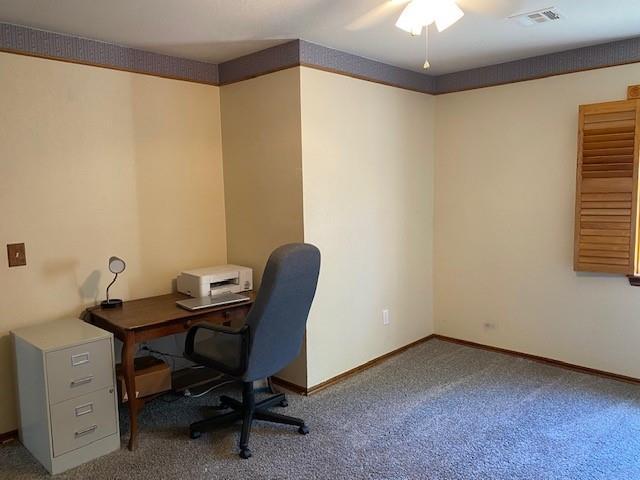 carpeted home office featuring visible vents, baseboards, and ceiling fan