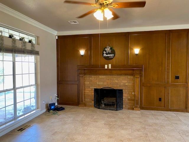unfurnished living room with visible vents, ornamental molding, light tile patterned floors, a brick fireplace, and ceiling fan