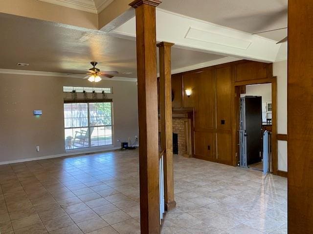 unfurnished room with ceiling fan, a brick fireplace, ornamental molding, and decorative columns