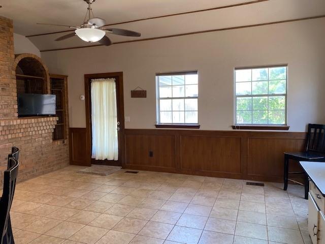 interior space with a wainscoted wall, a wealth of natural light, and a ceiling fan