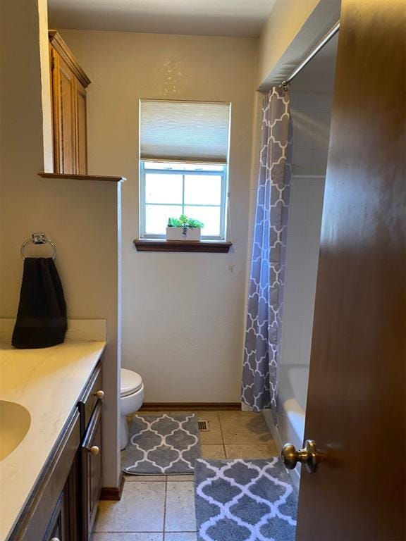 full bath with shower / bath combo, tile patterned floors, vanity, baseboards, and toilet