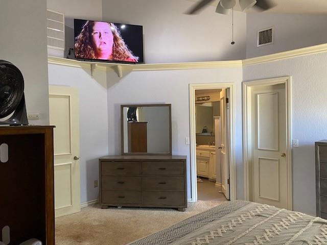 bedroom with ensuite bathroom, visible vents, carpet, vaulted ceiling, and ceiling fan