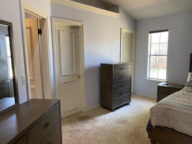 bedroom with vaulted ceiling, baseboards, and light colored carpet