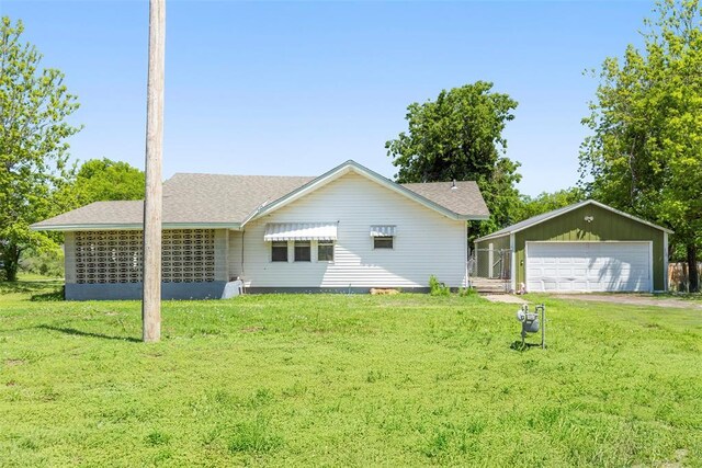 724 Maple St, Perry, OK 73077 - back of house featuring a lawn, an outdoor structure, roof with shingles, and a garage