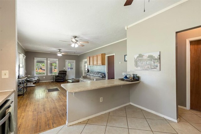 724 Maple St, Perry, OK 73077 - kitchen with ceiling fan, a breakfast bar area, light countertops, a peninsula, and ornamental molding