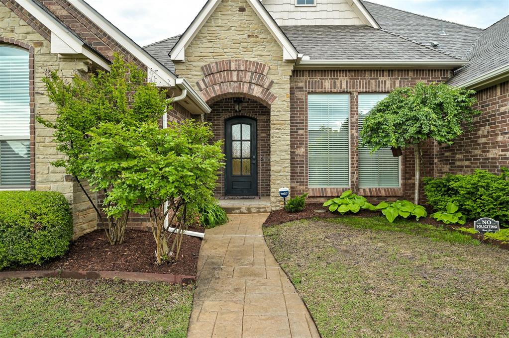 property entrance featuring a shingled roof, brick siding, and stone siding