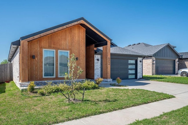 modern home with an attached garage, driveway, fence, and a front yard