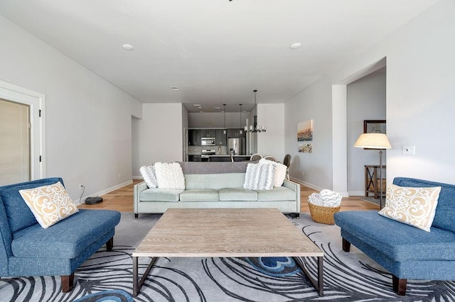 living area with light wood finished floors, baseboards, and a chandelier