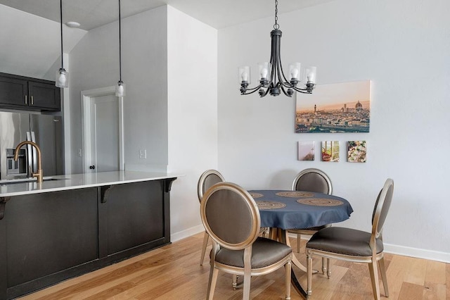 dining space featuring baseboards, light wood-style floors, and a chandelier