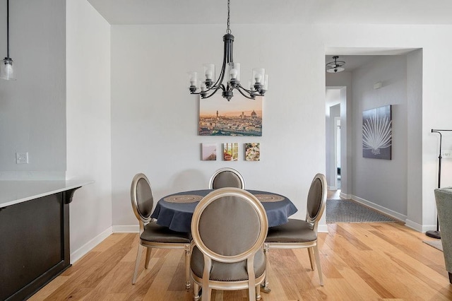 dining room featuring a chandelier, light wood-style floors, and baseboards