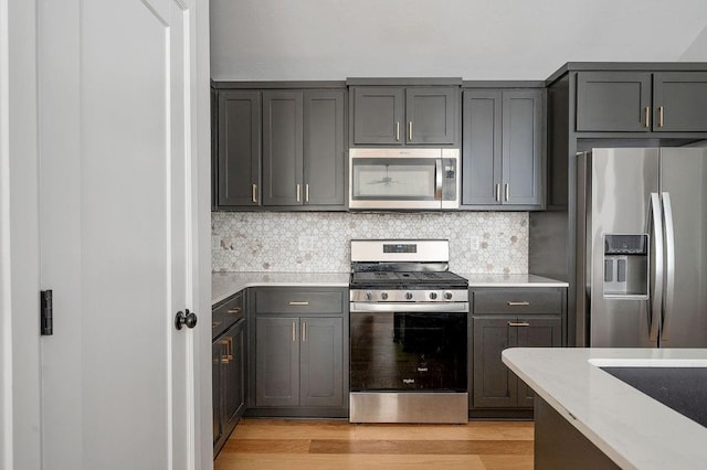 kitchen with backsplash, light wood-type flooring, gray cabinets, and stainless steel appliances