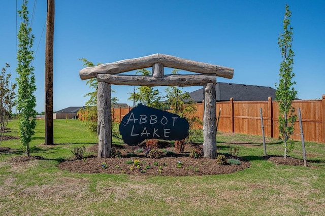 community sign with fence and a yard