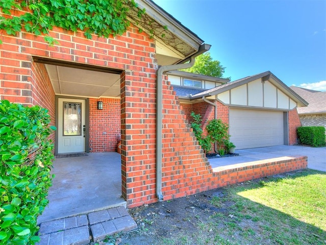 11609 Windmill Rd, Oklahoma City, OK 73162 - doorway to property featuring concrete driveway, an attached garage, brick siding, and board and batten siding