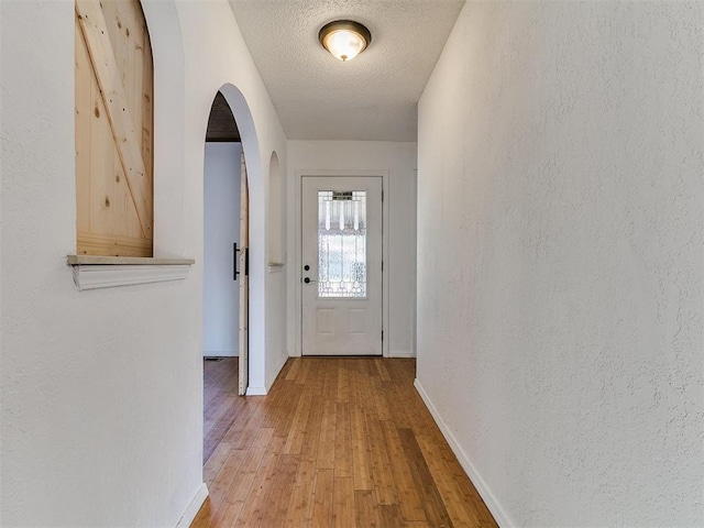 11609 Windmill Rd, Oklahoma City, OK 73162 - doorway featuring wood finished floors, baseboards, arched walkways, and a textured ceiling